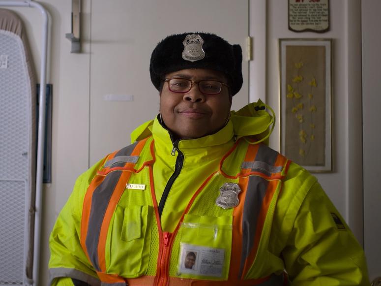 A security officer wearing bright yellow and orange safety gear.