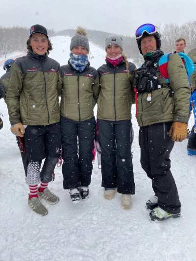 Four athletes in matching team jackets standing on the snow