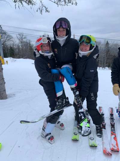 Three athletes standing on their skis at the top of a run