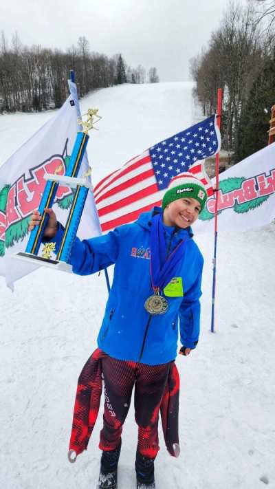 Athlete wearing medals and carrying a flag at the top of the hill