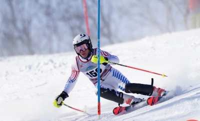 Racer in a blue and white speed suit passing a slalom gate