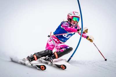 Racer in a pink and blue suit clearing a blue slalom gate