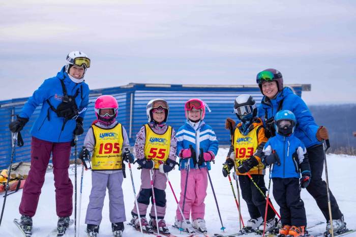 Coach lined up on the snow with a row of the youngest racers in bibs