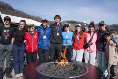 Team gathered around an outdoor fire pit after a race