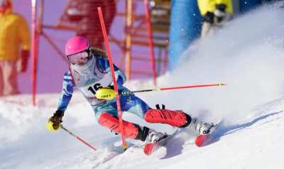 Racer in a pink helmet carving a slalom turn past a gate
