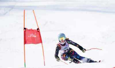 Racer tucking between red giant slalom panels on open snow