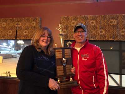 Two adults holding a large engraved trophy plaque at the awards banquet