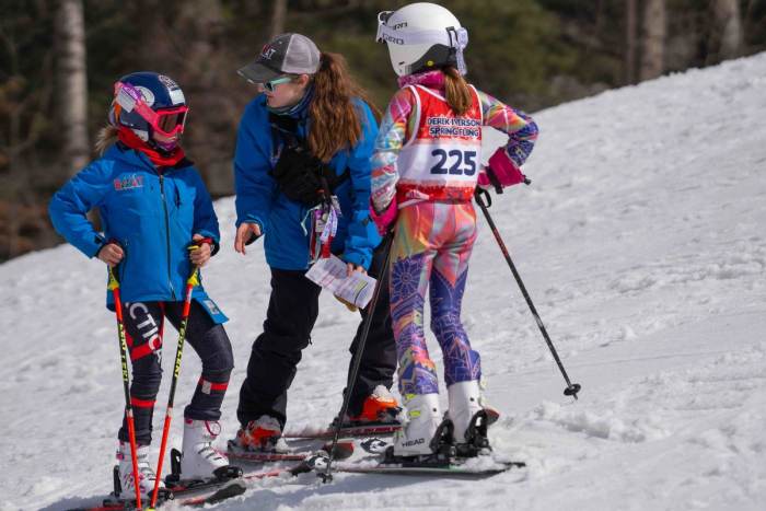 Coach talking through a run with athletes at the side of the course
