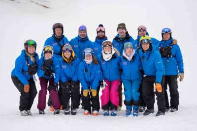 Full team group photo in blue SWAT jackets on the snow
