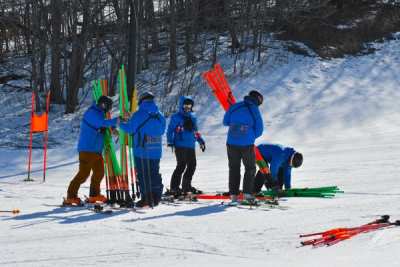 Coaches setting a course, bundles of gate poles laid out on the snow