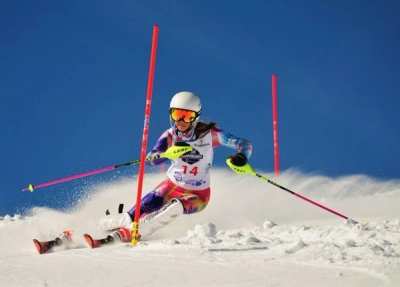 Racer carving past pink slalom gates under a clear blue sky