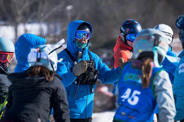 Young athletes in helmets and race bibs huddled together at the start