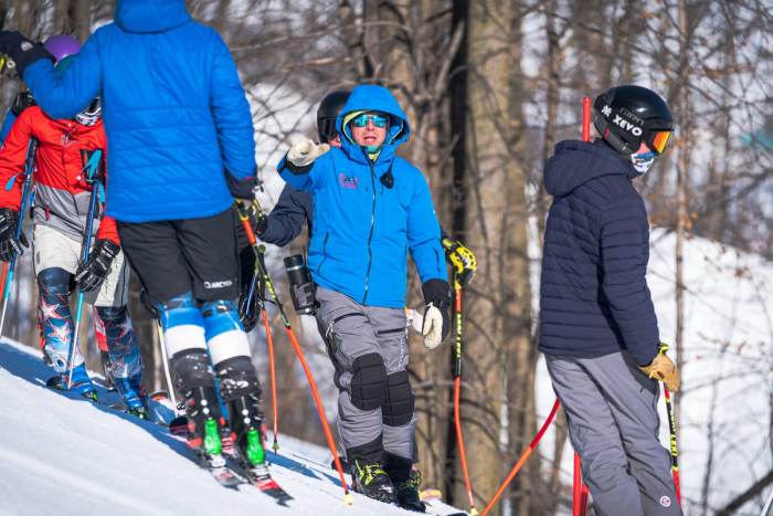 Coaches and athletes gathered at the top of a course in the trees