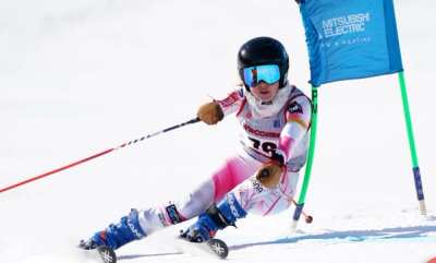 Racer in a pink suit passing a sponsored giant slalom panel