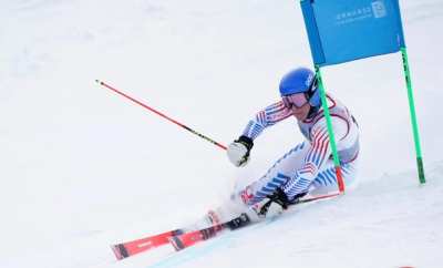 Racer low through a giant slalom gate, inside hand down