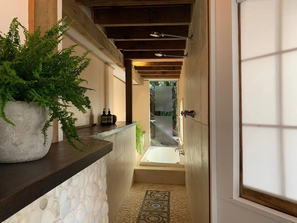 Narrow stone-tiled bathroom with a freestanding bath, ferns and frosted glass
