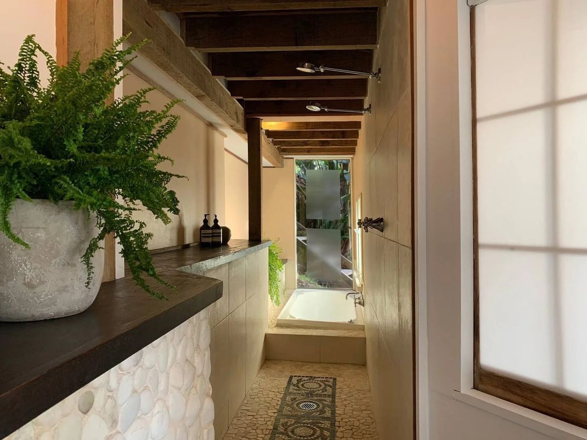 Narrow stone-tiled bathroom with a freestanding bath, ferns and frosted glass