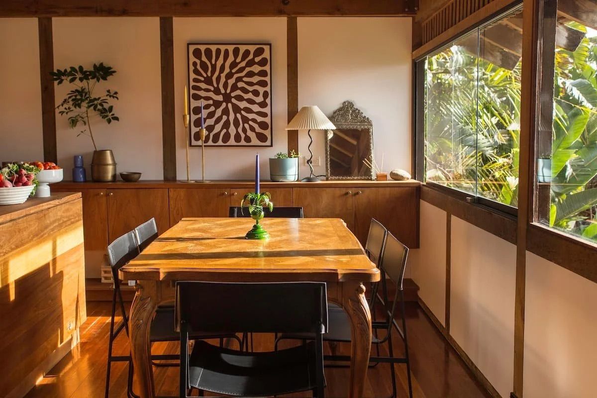 Timber-paneled dining nook with an abstract framed print, antique mirror and warm lamp light