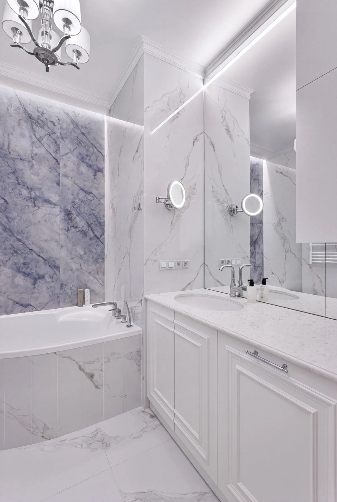 Bagno in marmo, nei toni bianco e azzurro-grigio, con mobili classici a pannelli