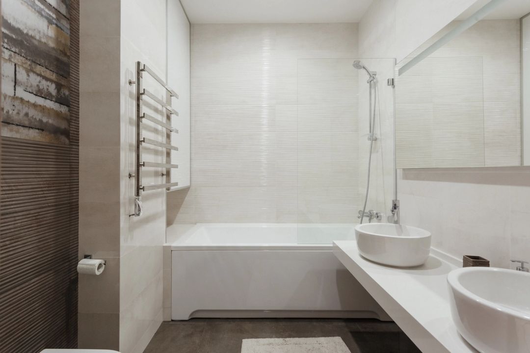 Bagno con vasca, doppio lavabo d'appoggio su piano continuo e rivestimento in gres rigato