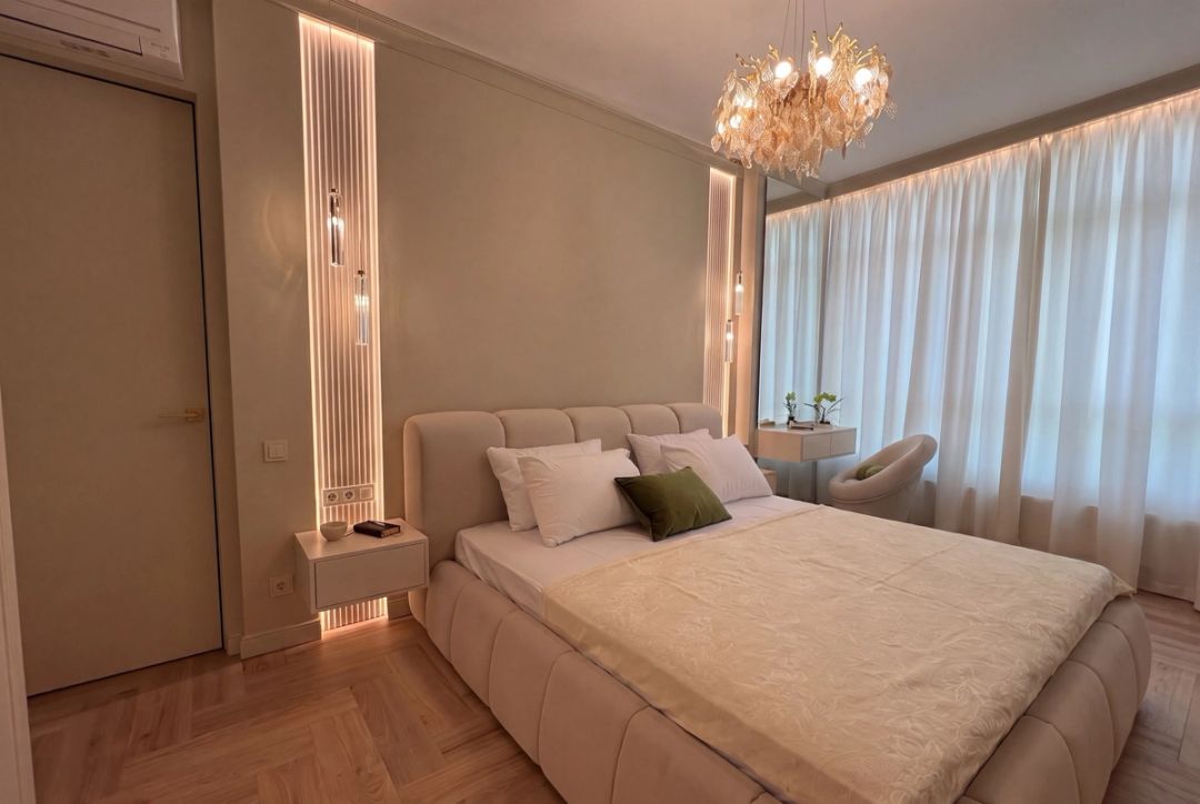 Camera da letto con testiera imbottita, lampadario in vetro dorato e specchiera illuminata