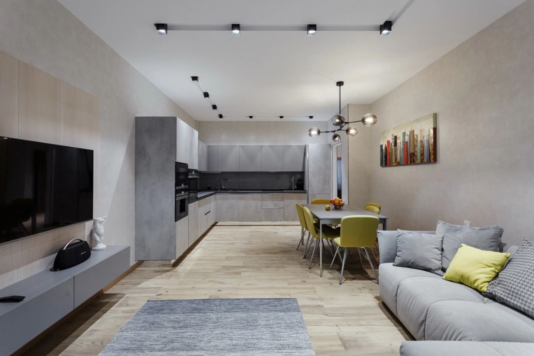 Zona giorno open space con cucina in effetto cemento, tavolo da pranzo e sedute verde lime