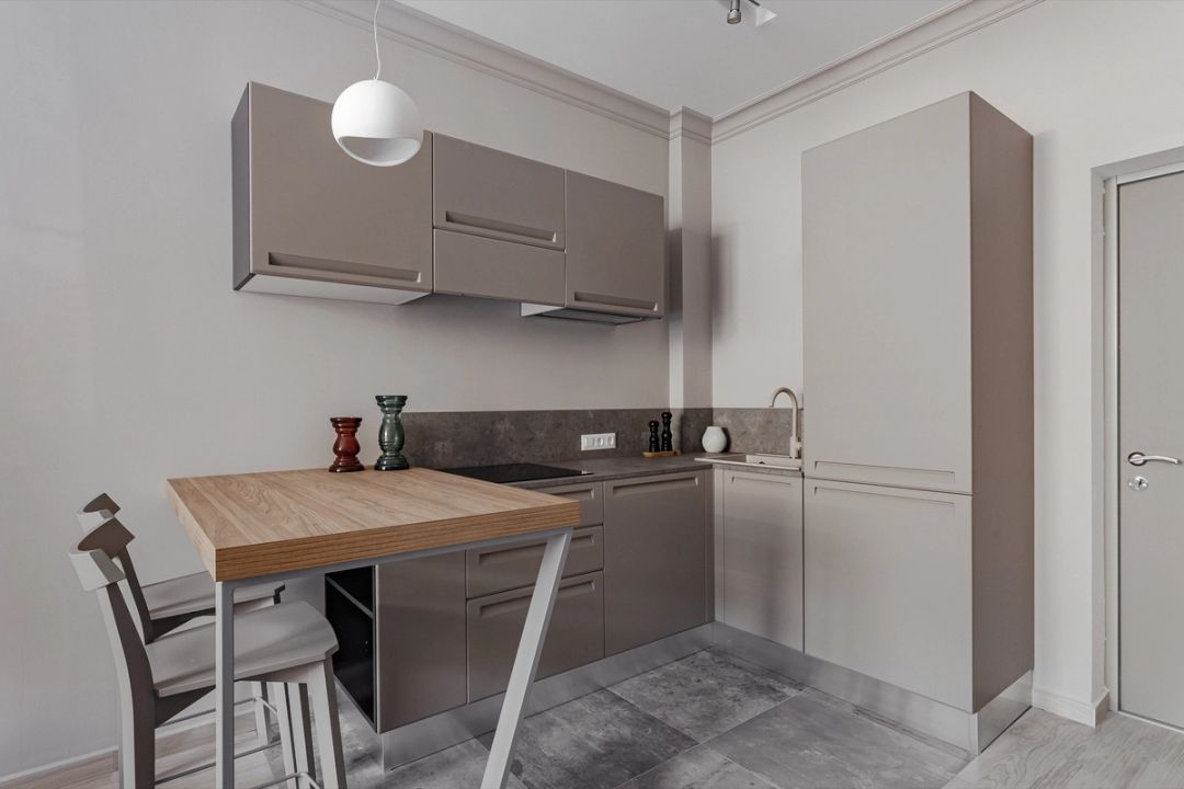 Cucina ad angolo con ante grigio tortora opache, penisola snack in rovere e sgabelli alti.