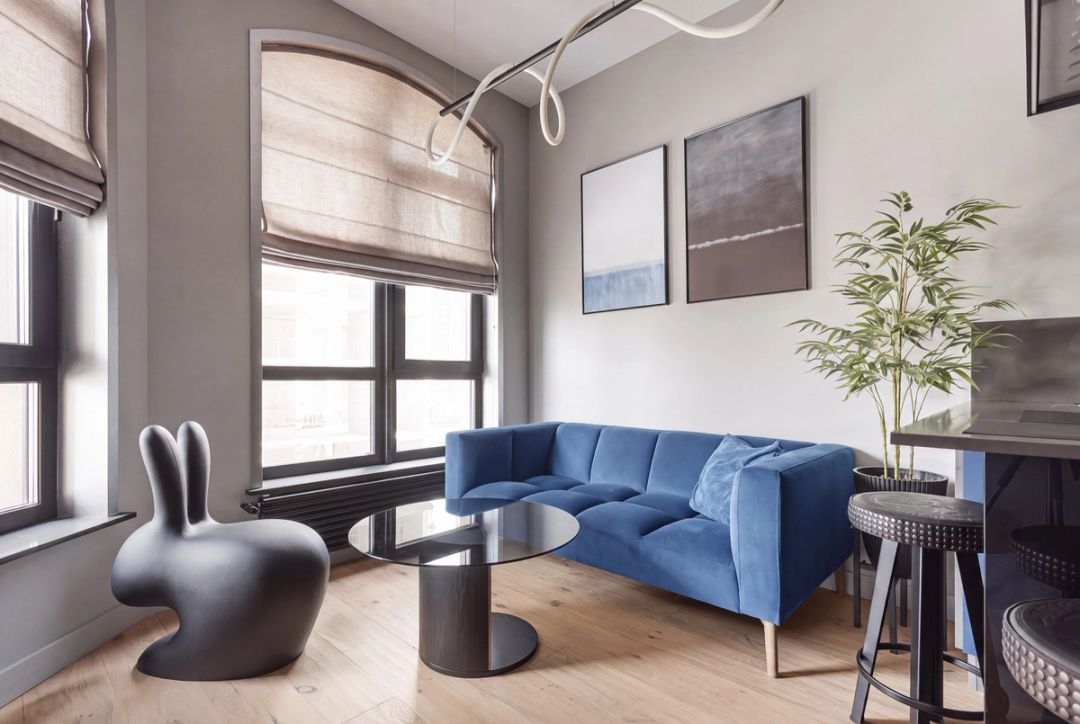 Compatta zona giorno con divano in velluto blu, décor scultoreo e una sinuosa lampada al neon