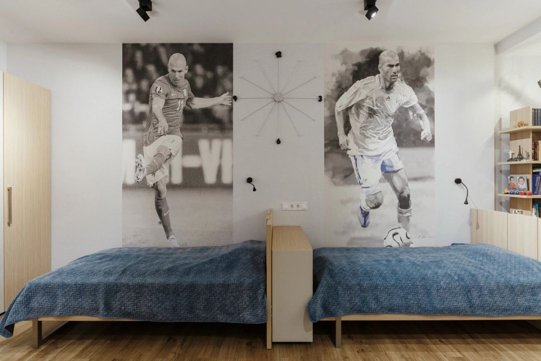 Cameretta per due con letti gemelli, murales a tema calcistico e armadiature in legno chiaro
