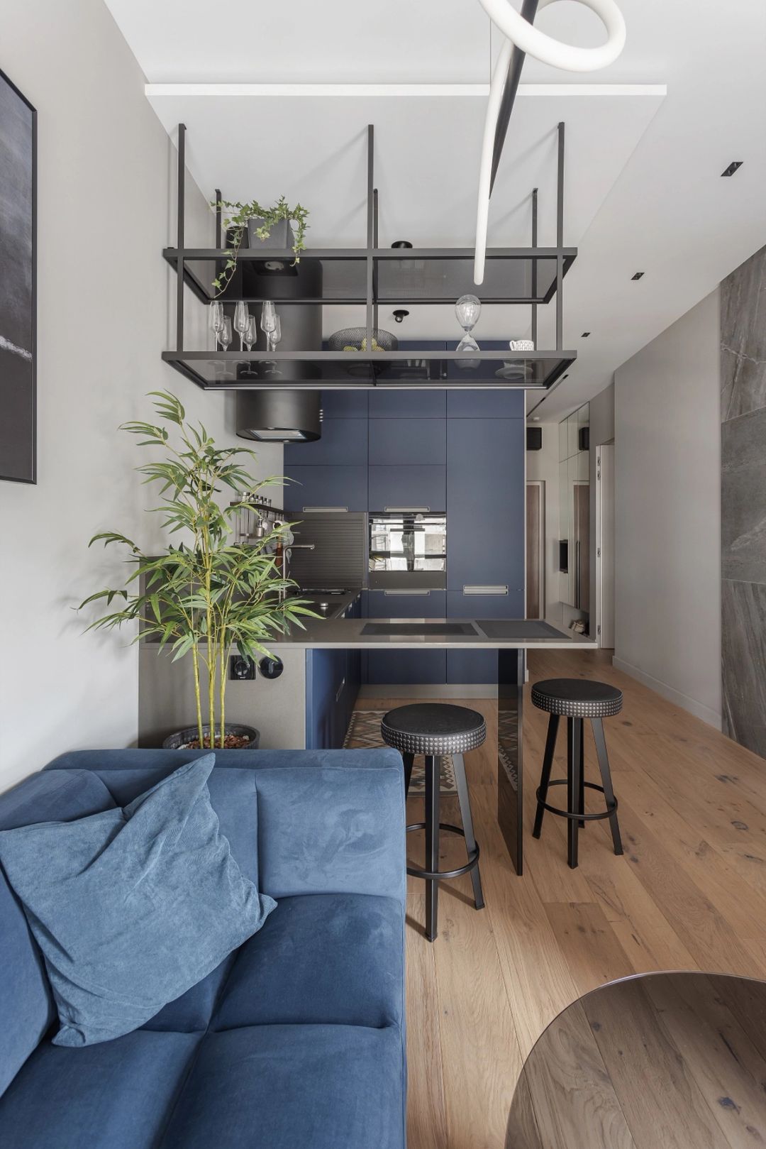 Cucina e zona giorno a pianta aperta, con ante blu intenso e una mensola in vetro sospesa
