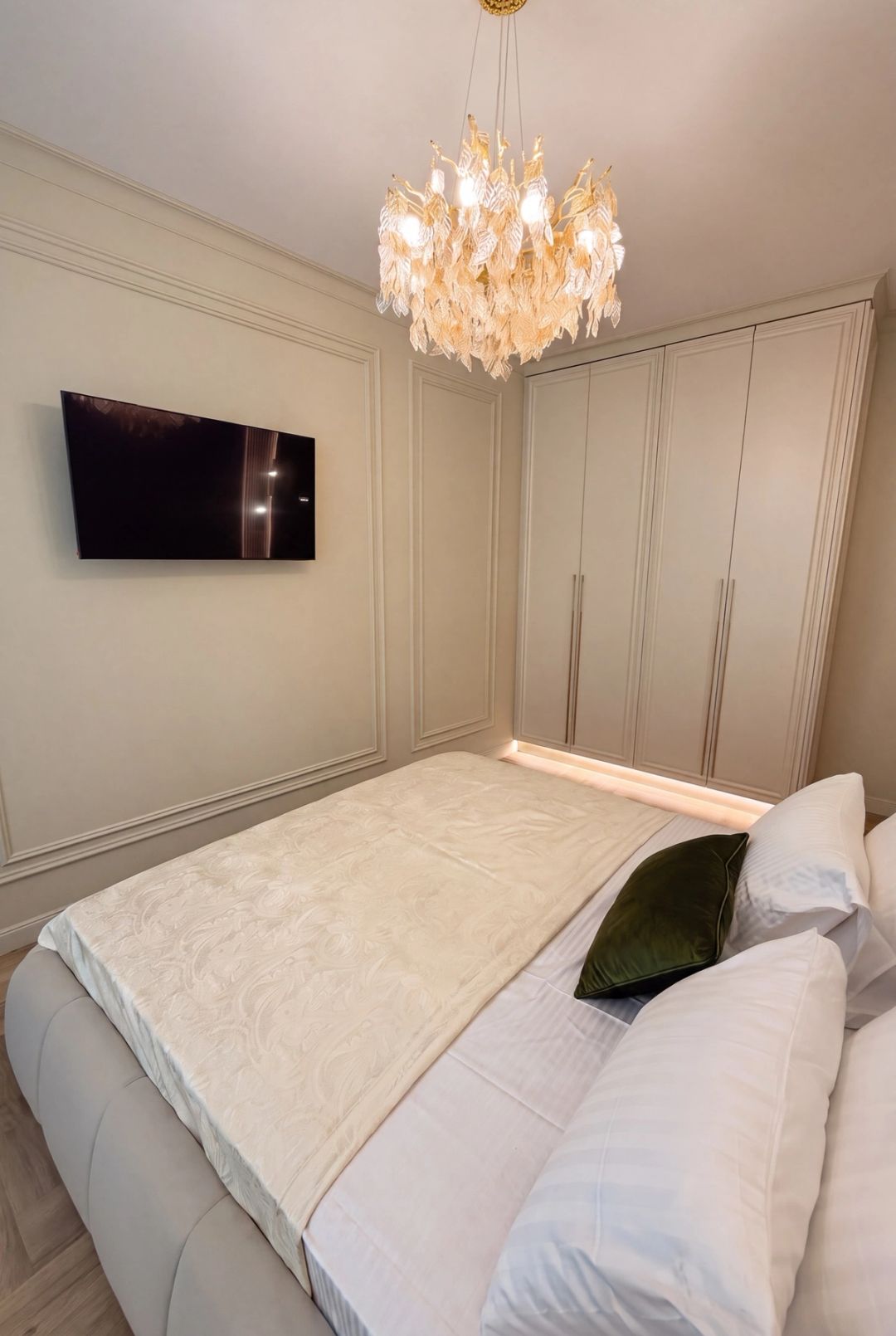 Camera da letto in stile classico contemporaneo con boiserie a pannelli, cabina armadio e TV a parete