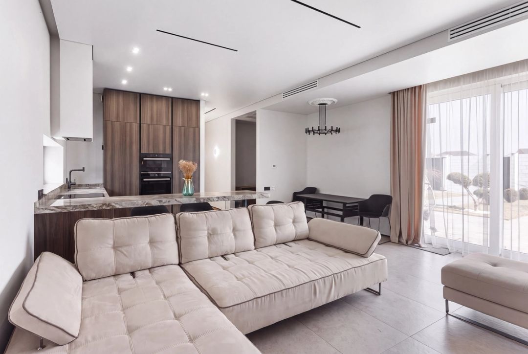 Soggiorno e cucina a pianta aperta in una casa moderna, con mobili in legno caldo e accesso al giardino