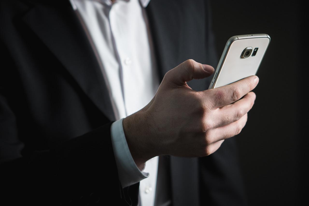 Un hombre con un celular en la mano enviando un mensaje