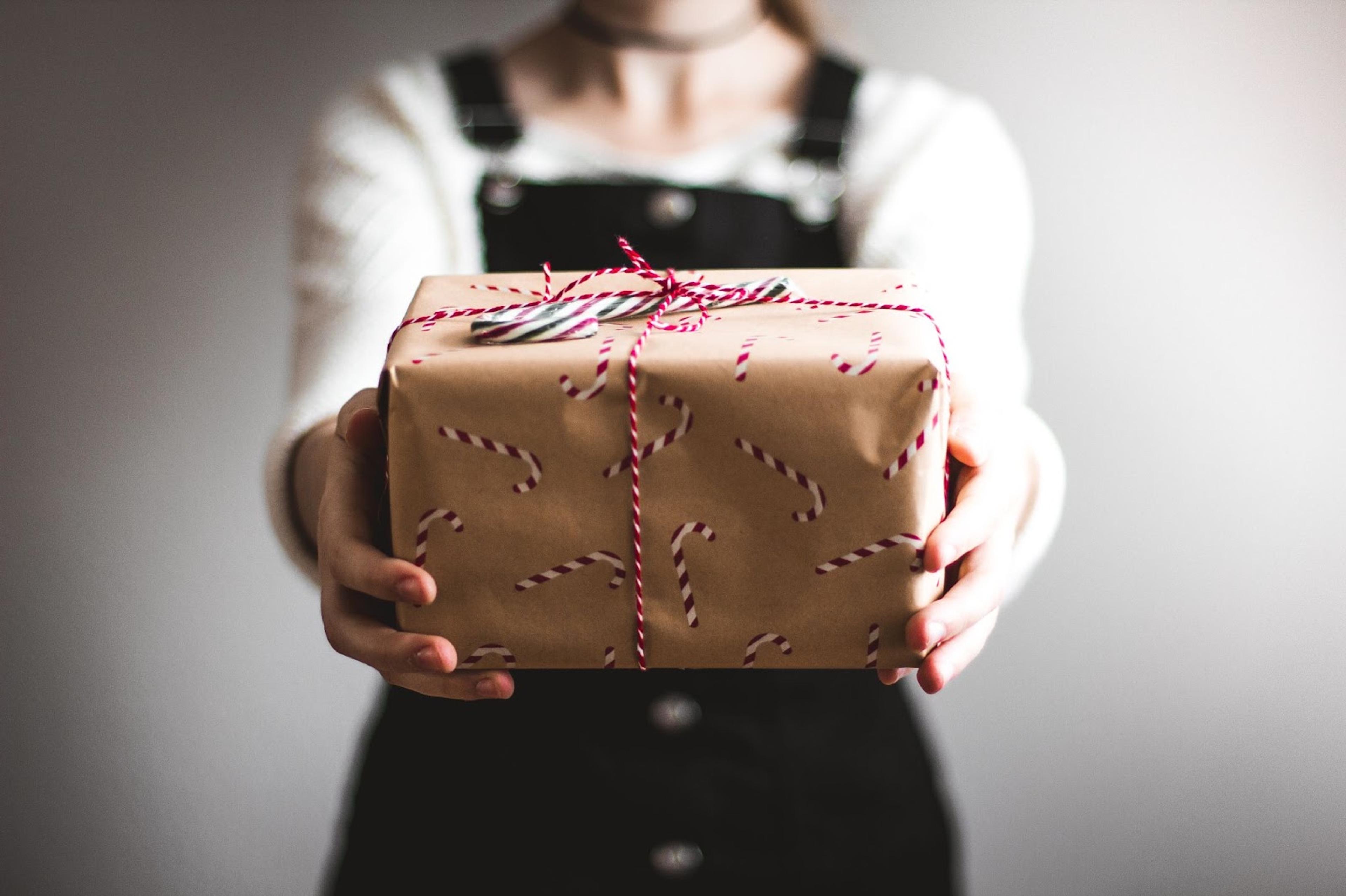 Manos de mujer entregando un regalo navideño