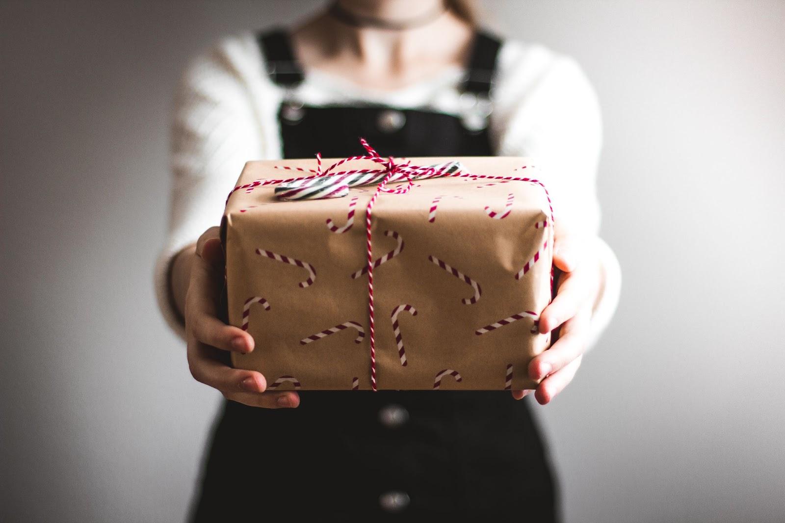 Manos de mujer entregando un regalo navideño