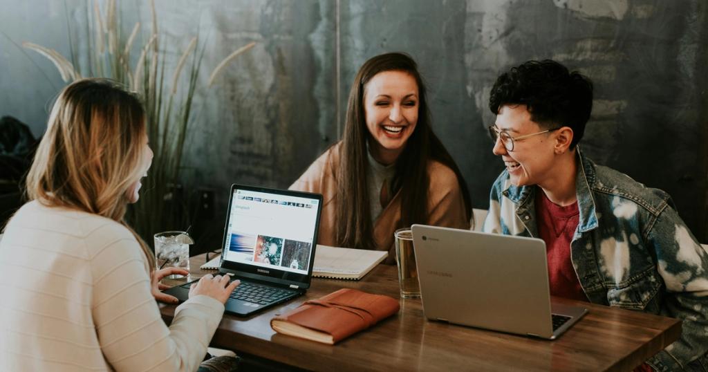 Graduate student organizing thesis references on a laptop with stacks of research papers nearby