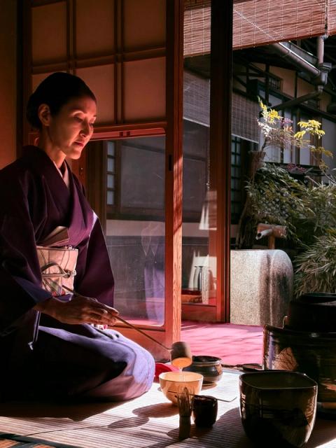 Una anfitriona en kimono prepara el té en una sala de tatami