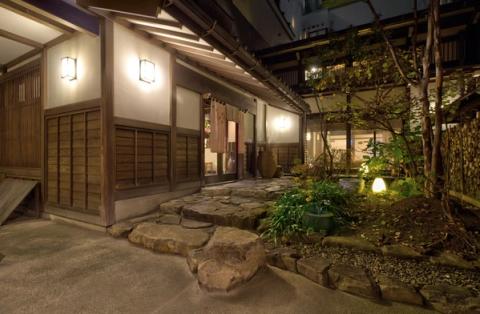 Pasillo de madera de un ryokan tradicional japonés junto a un jardín, de noche