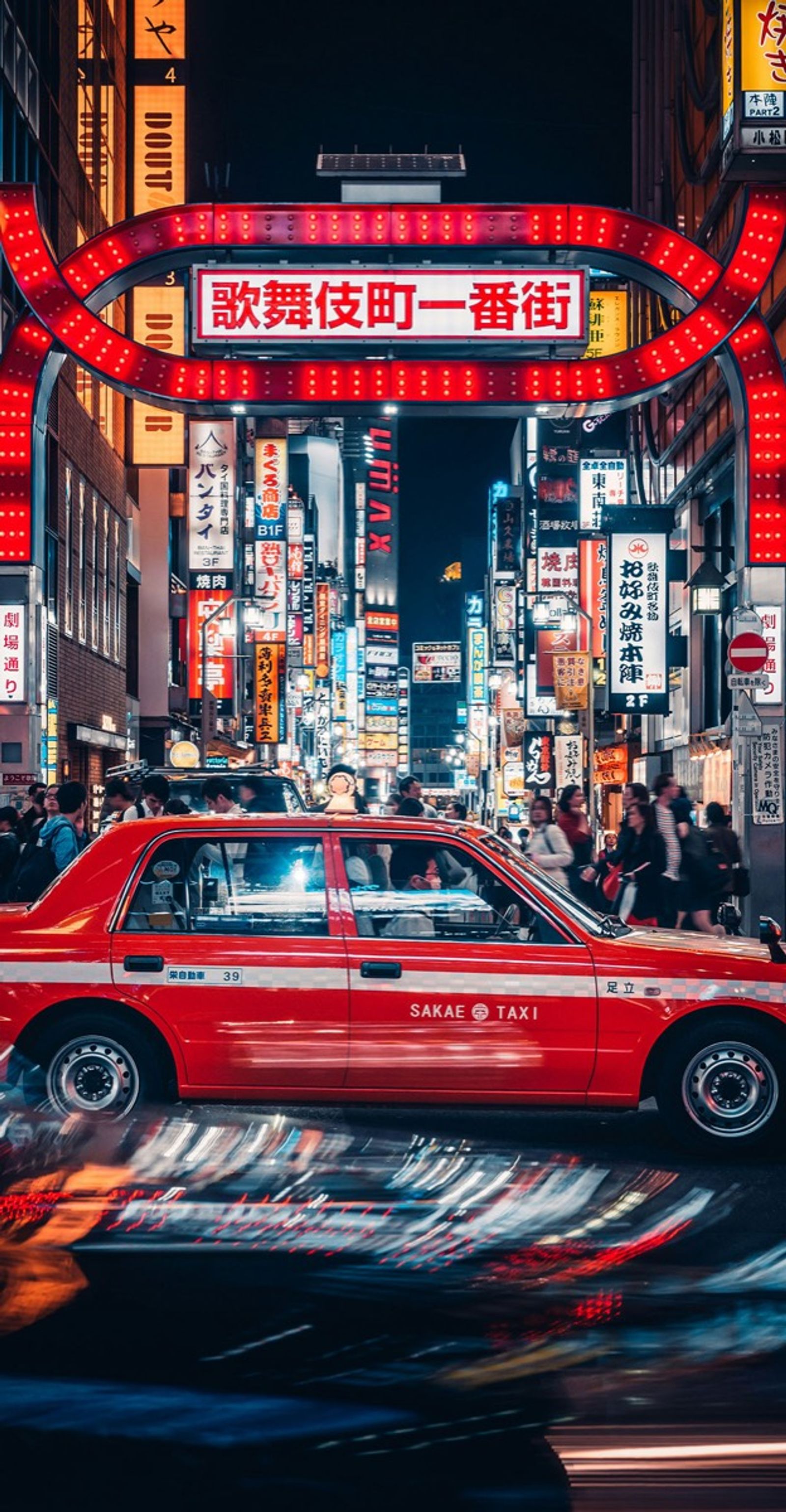 Un taxi rojo bajo el arco luminoso de Kabukicho, en Tokio