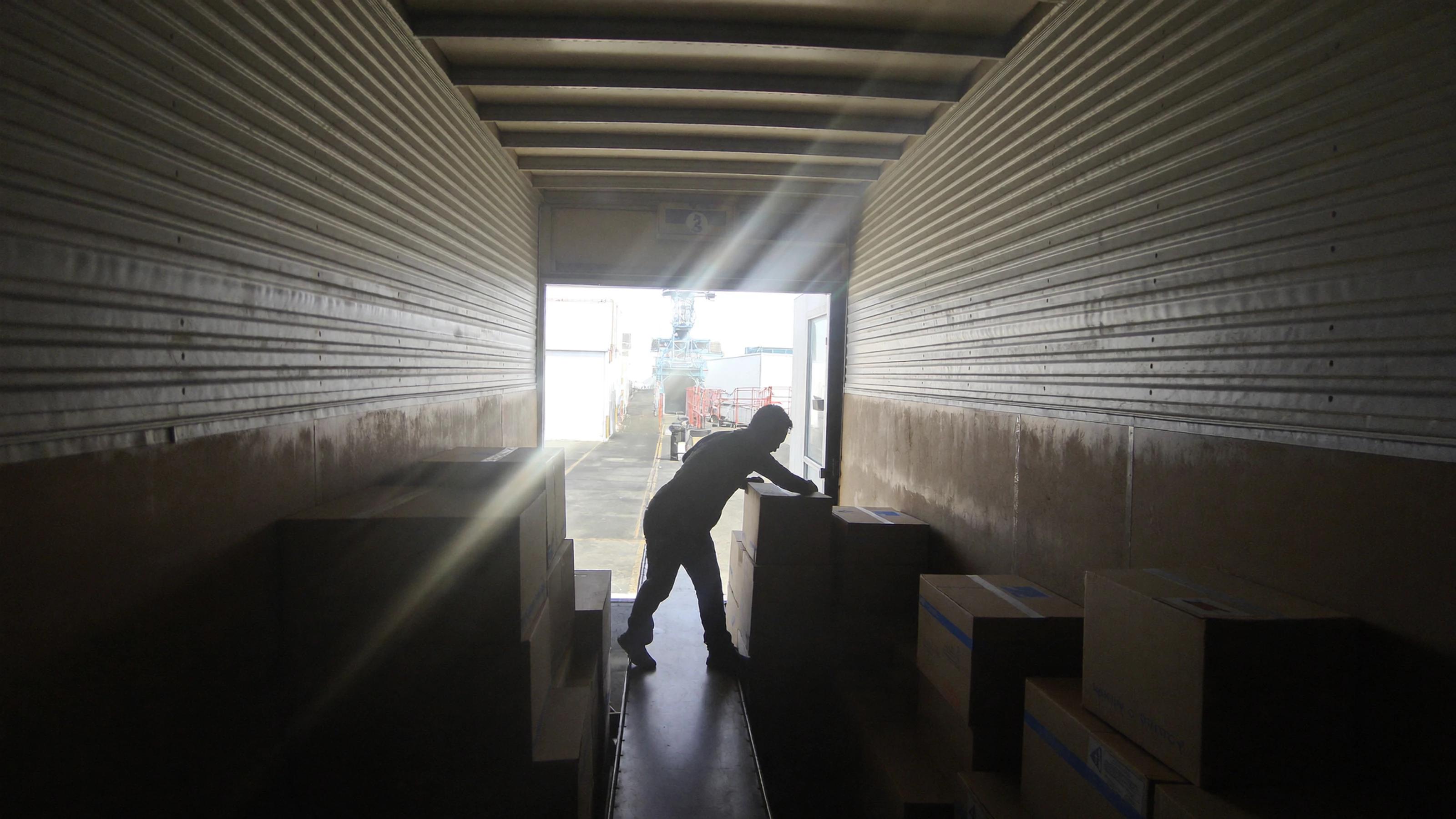 Warehouse worker moving boxes inside a delivery truck