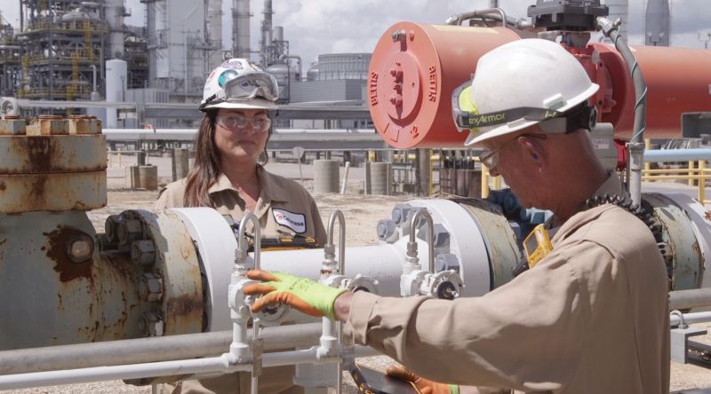 Manufacturing employees wearing safety gear inside an industrial facility