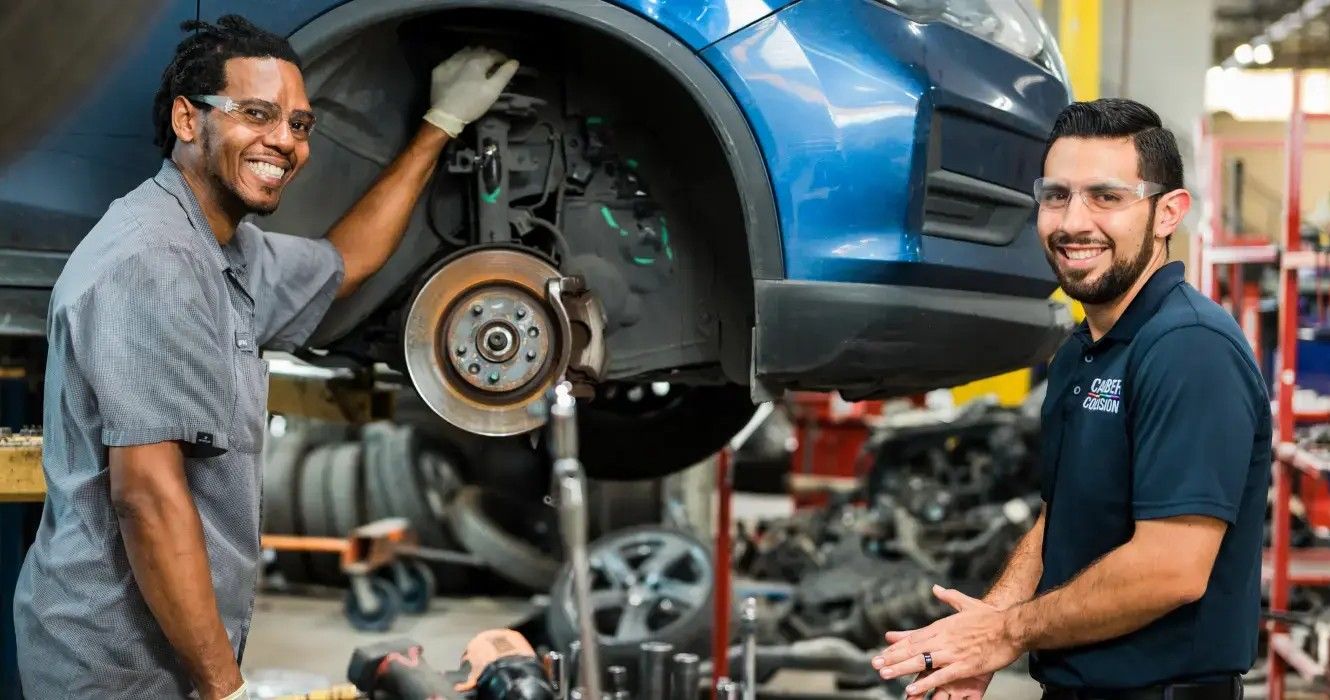 Two automotive technicians inspecting a vehicle together