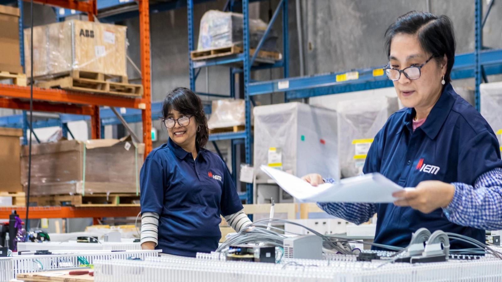 Two manufacturing employees working beside production equipment