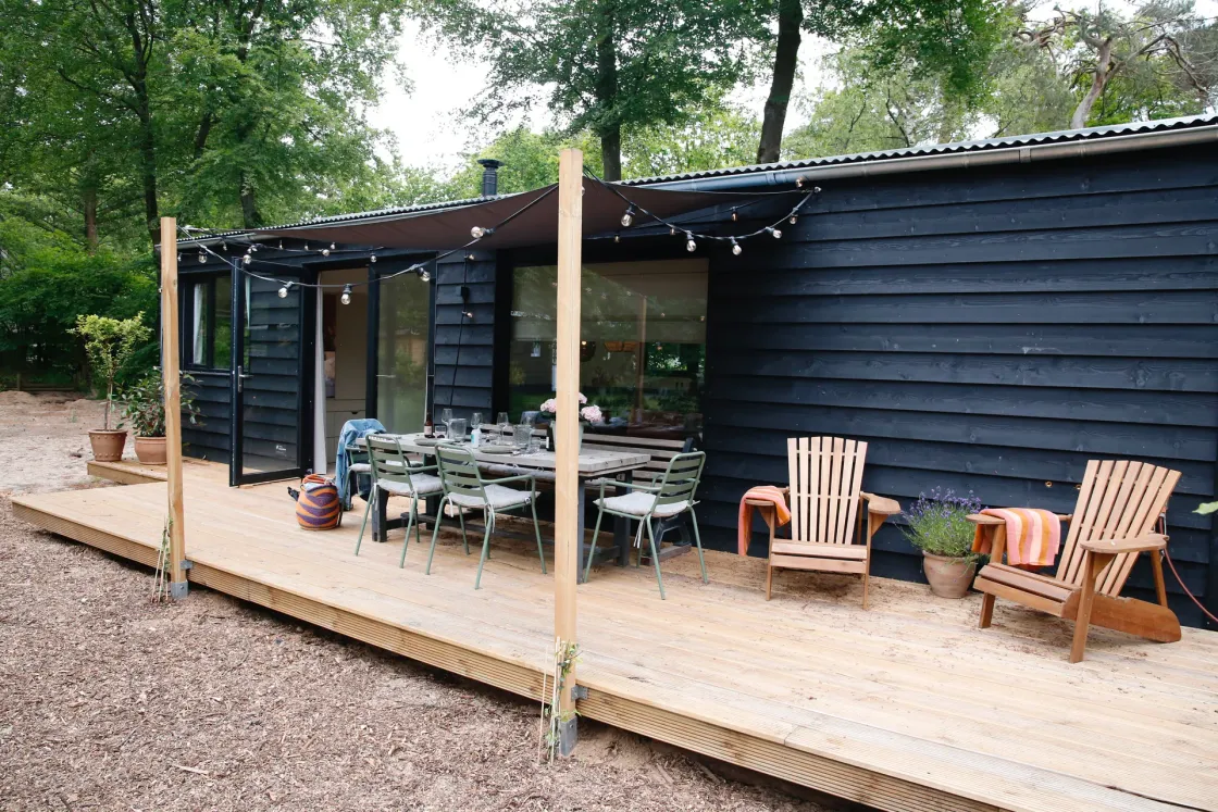 De Buitenplek van Stek: houten terras met lampjes in het bos