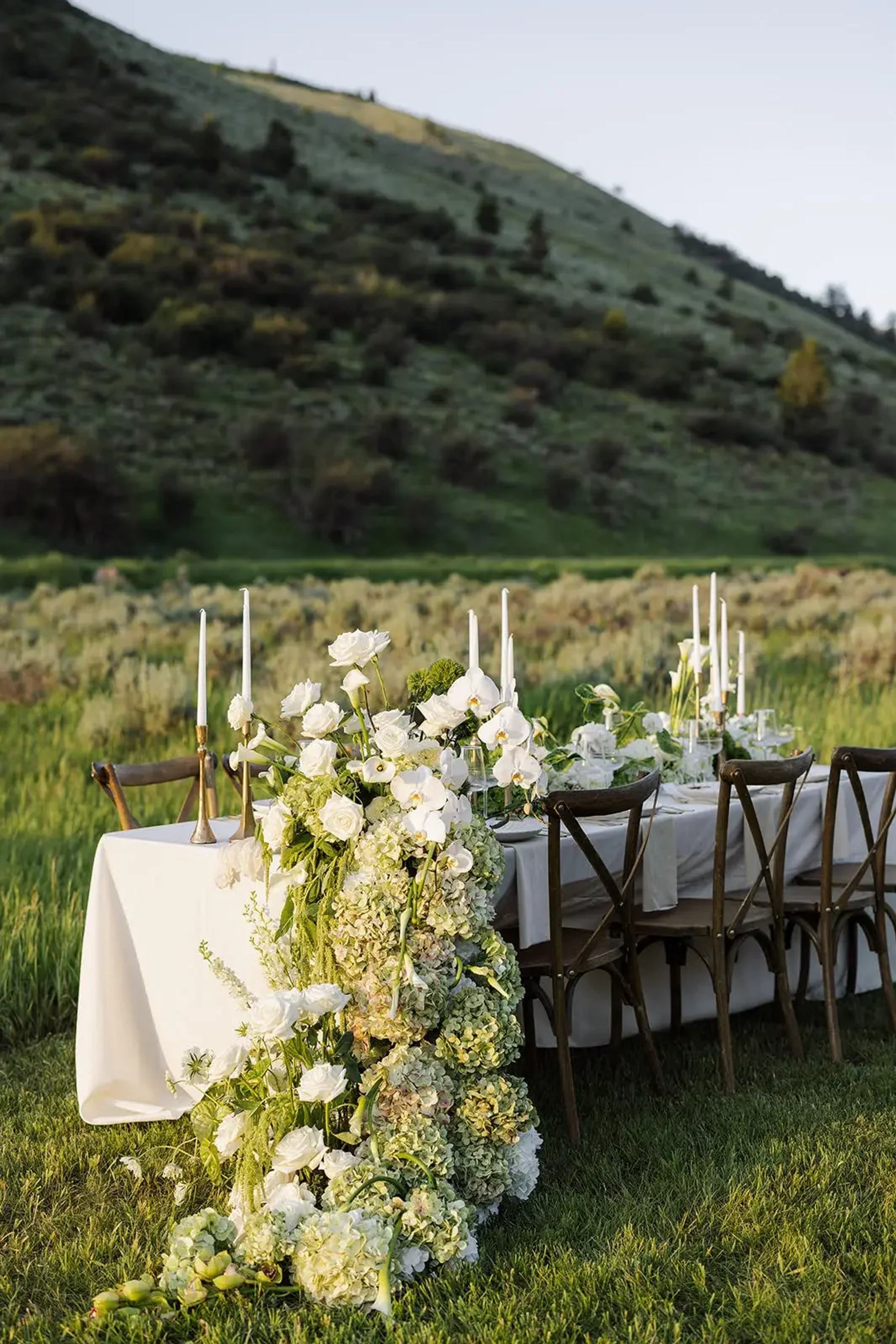 White floral installation flowing from an outdoor reception table