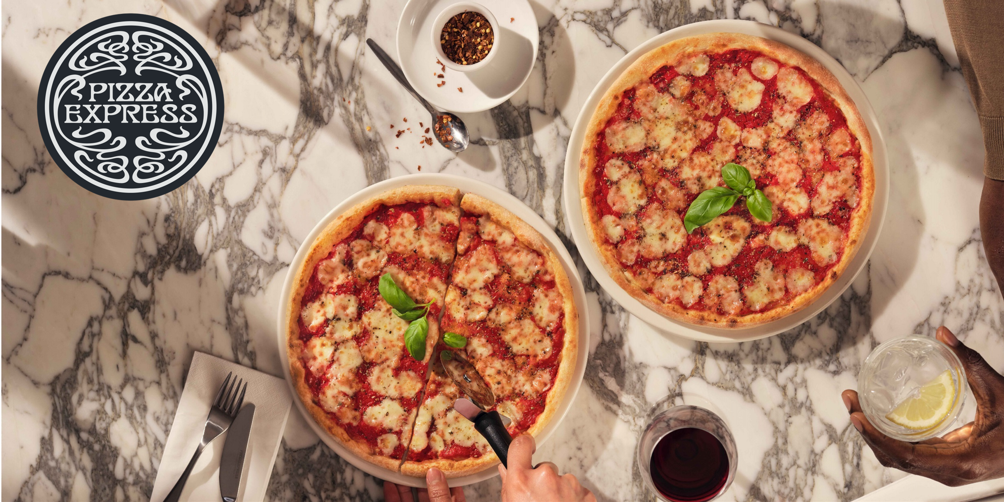 two pizzas on a table with a pizza express logo