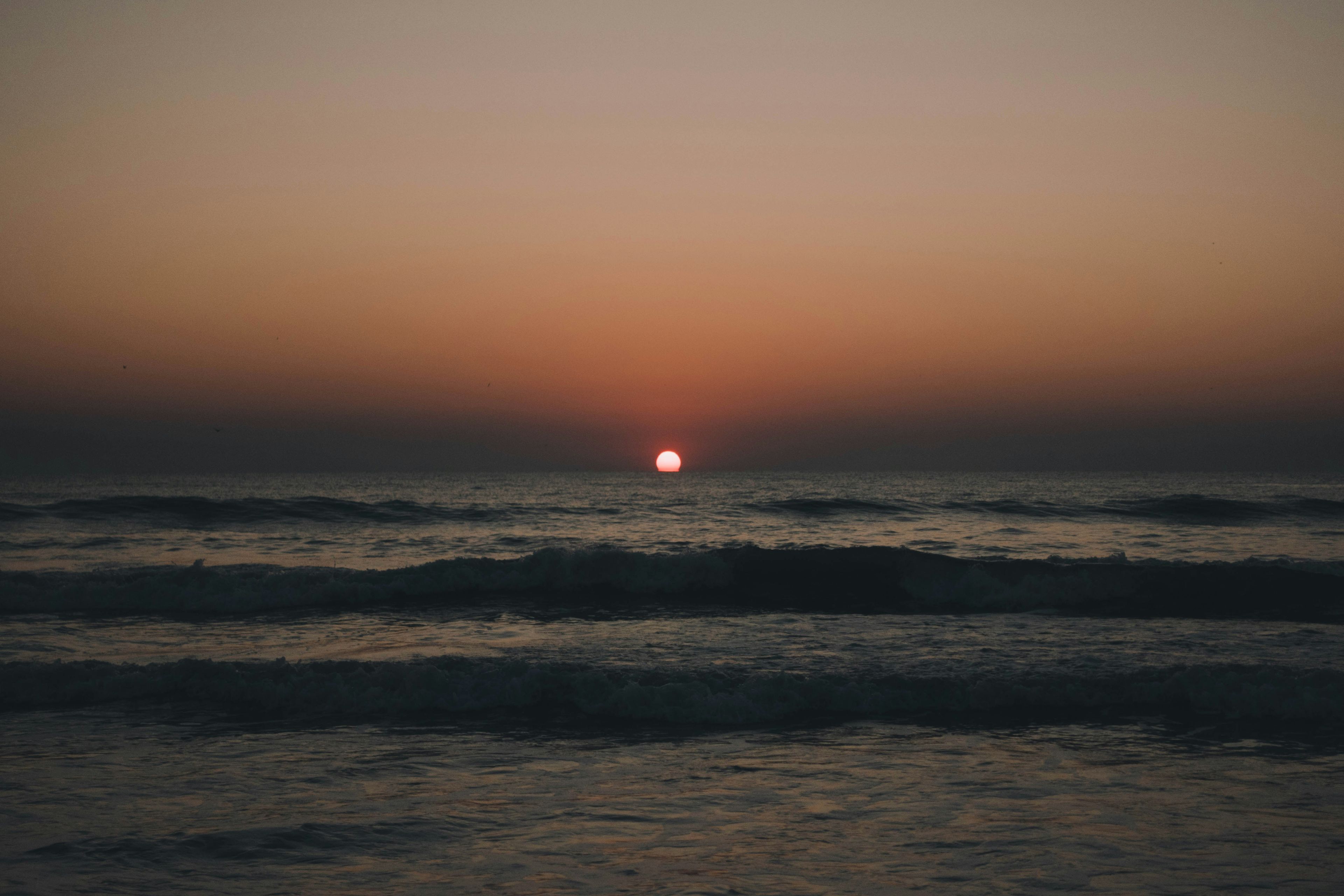 the sun is setting over the ocean .