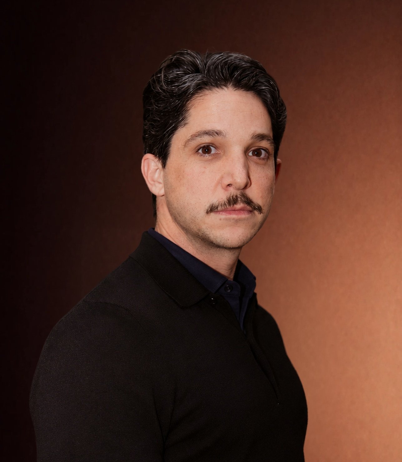 Portrait de Benjamin Paoli Cohen sur un fond de studio aux tons chauds.