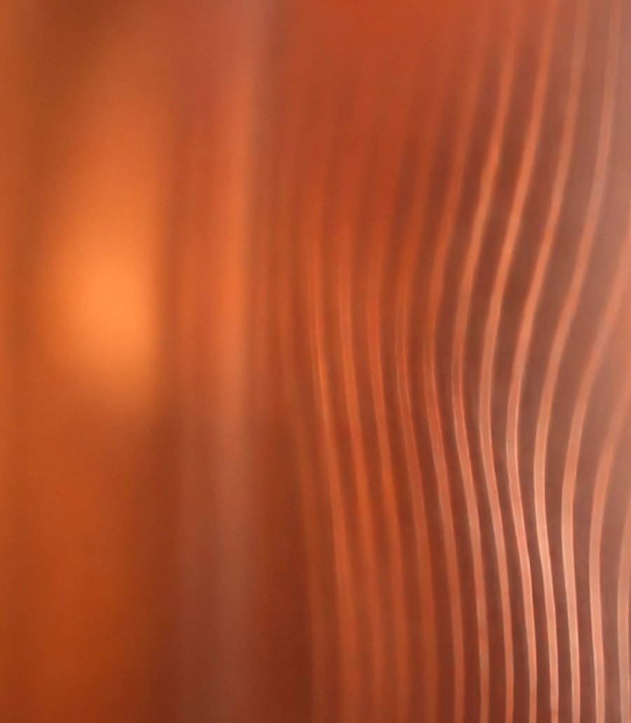 Une lumière cuivrée et chaude ondule sur une surface cannelée.