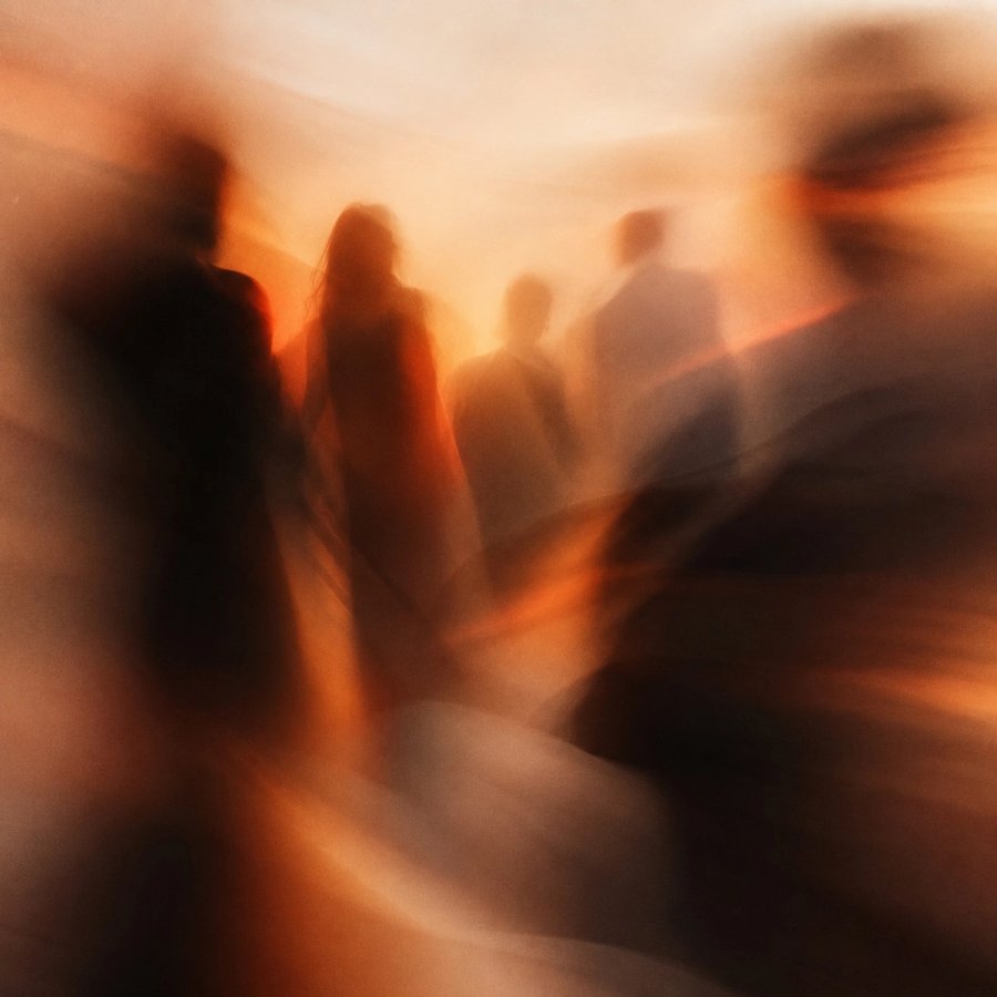 Des silhouettes floues de personnes réunies dans une lumière ambrée et chaleureuse.